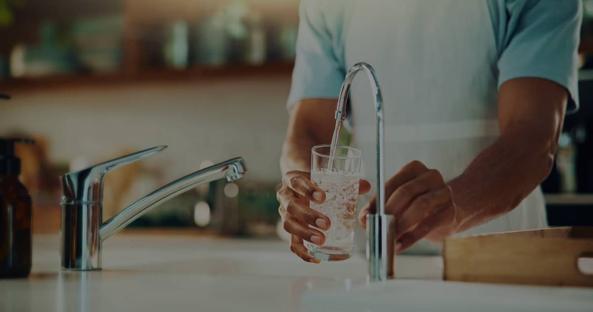 Filling glass with clean water at modern faucet